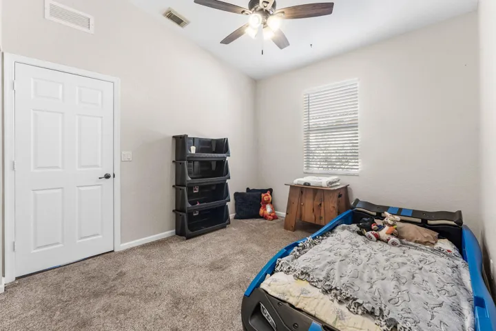 Carpeted room featuring a neutral color palette, a multi-paneled door, and a window with horizontal blinds