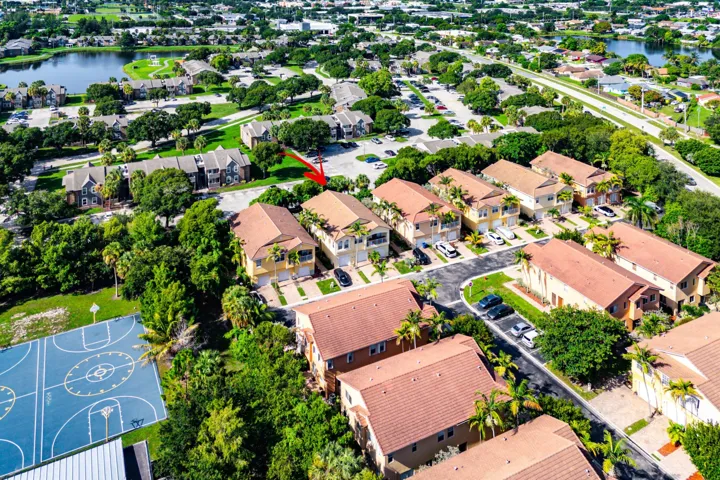 Aerial perspective showcasing the residential community with multiple detached and attached structures, tile roofs, and surrounding green spaces