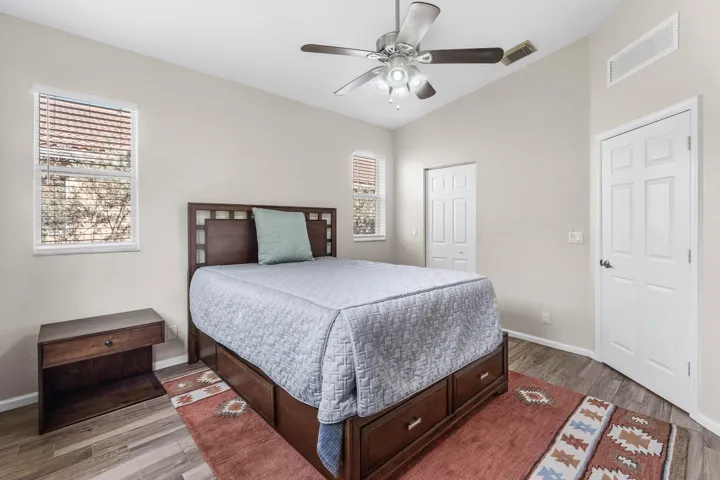 High ceiling room with wood-tile flooring, a ceiling fan with integrated lighting, and walk-in closet