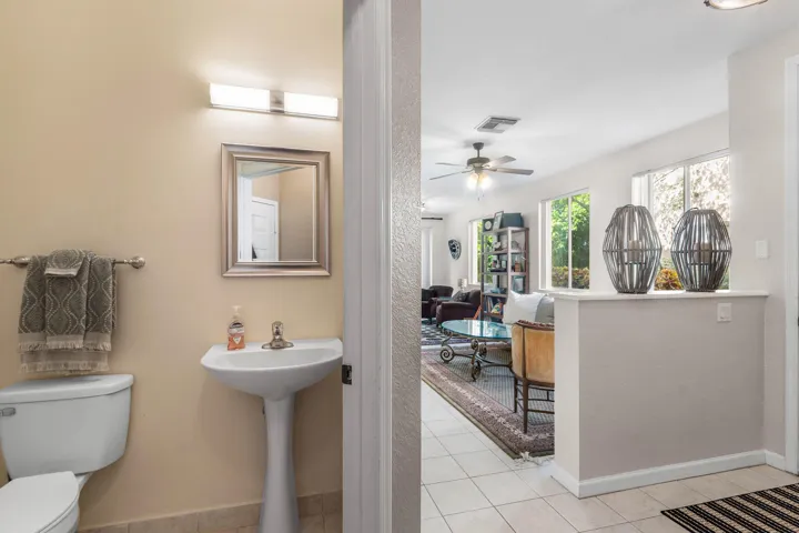 Powder room featuring a pedestal sink, framed mirror, and a two-bulb vanity light fixture