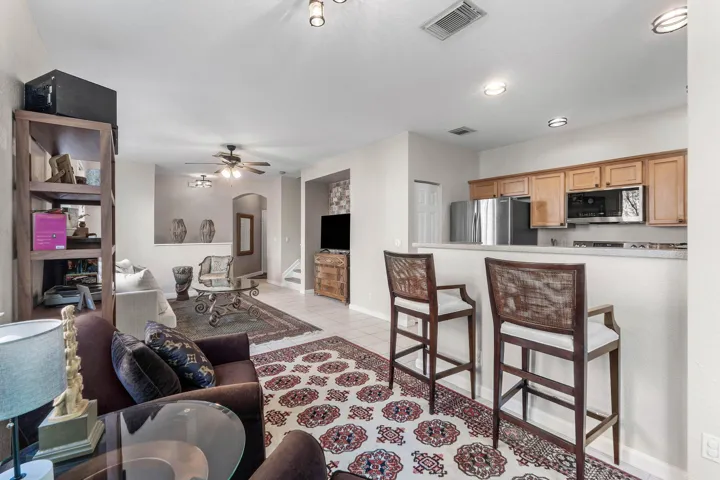 Open-concept living area featuring tile flooring, ceiling fans, and an open kitchen with counter seating