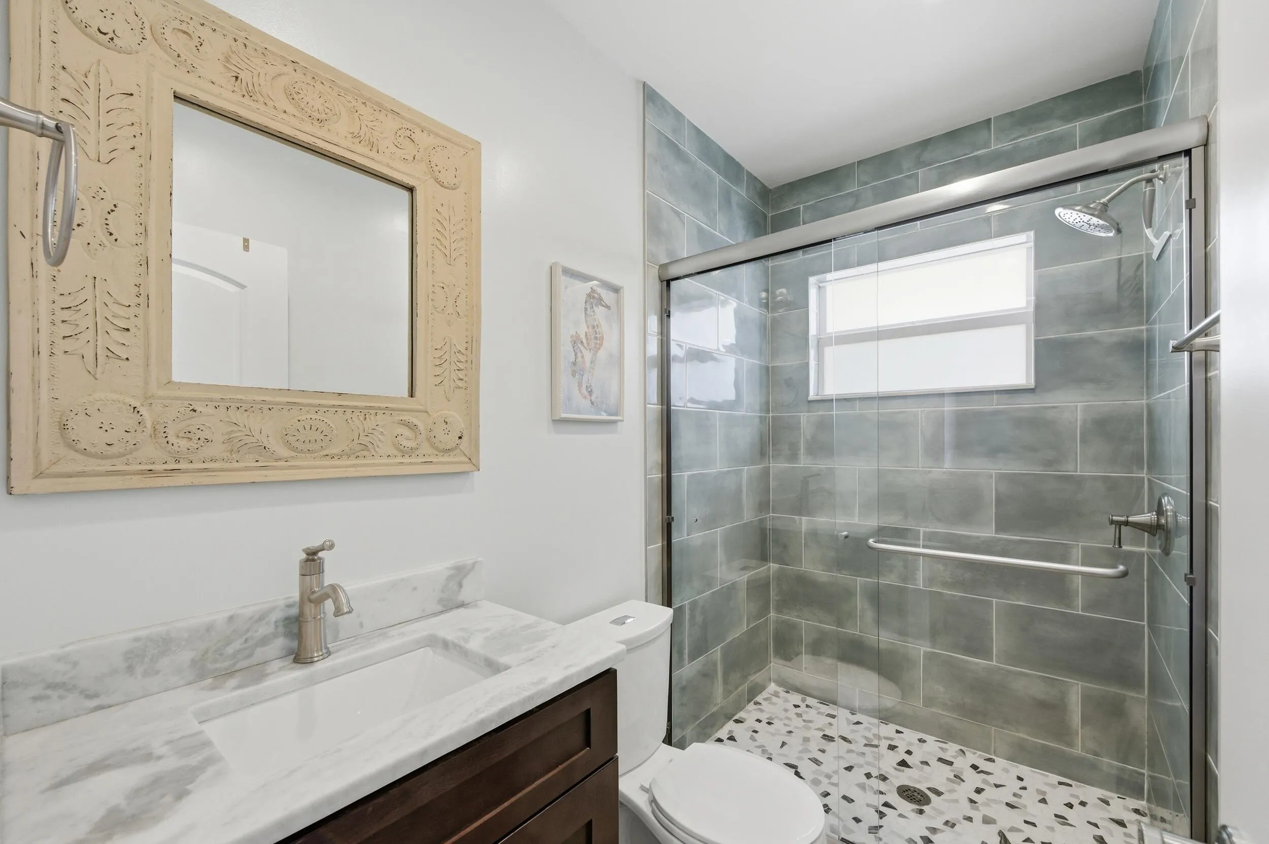 Bathroom featuring a glass-enclosed shower with gray subway tile surround and pebble-style flooring