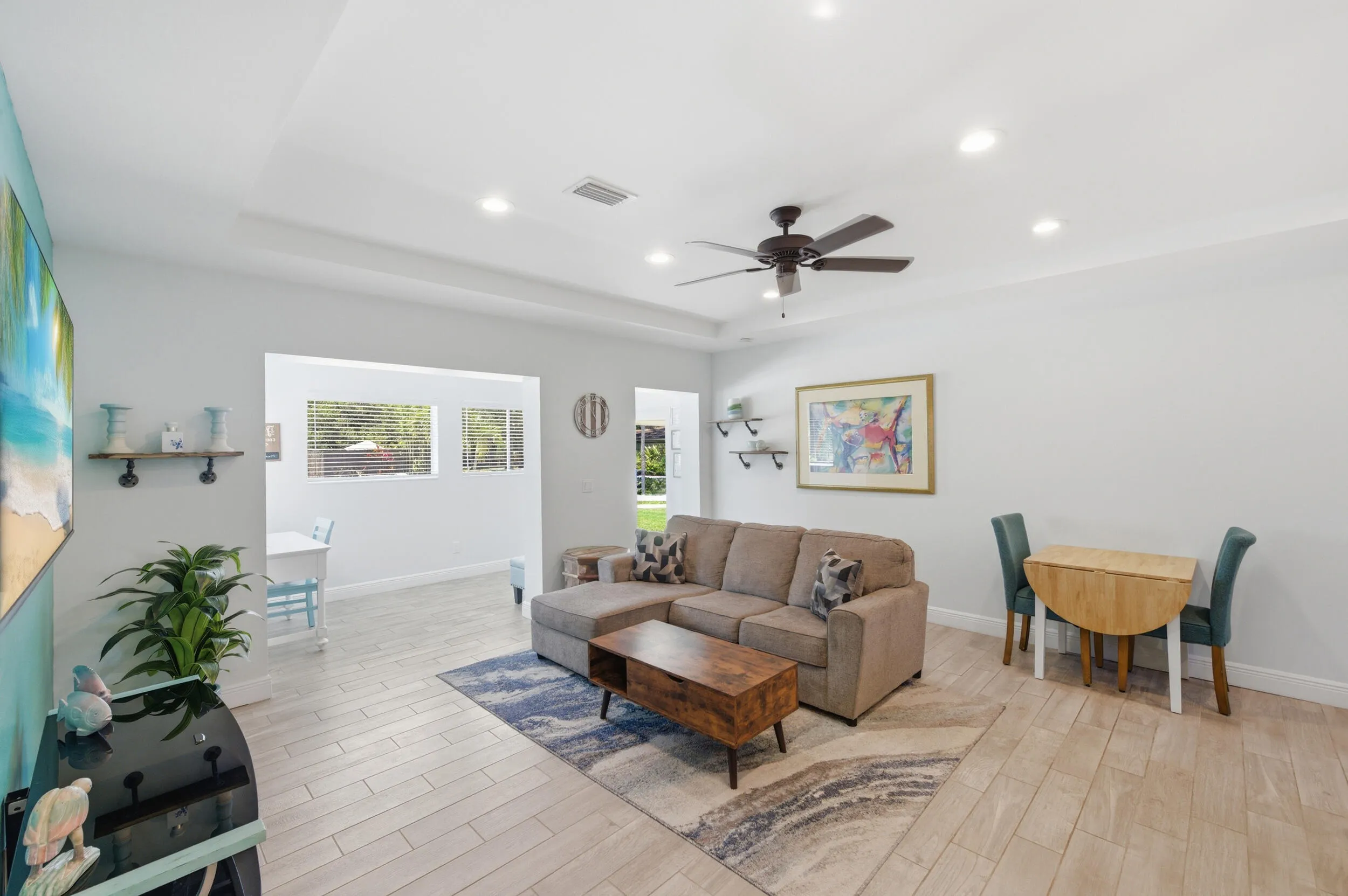 Open-concept living area featuring wood-finish flooring, recessed lighting, a ceiling fan, and a tray ceiling detail