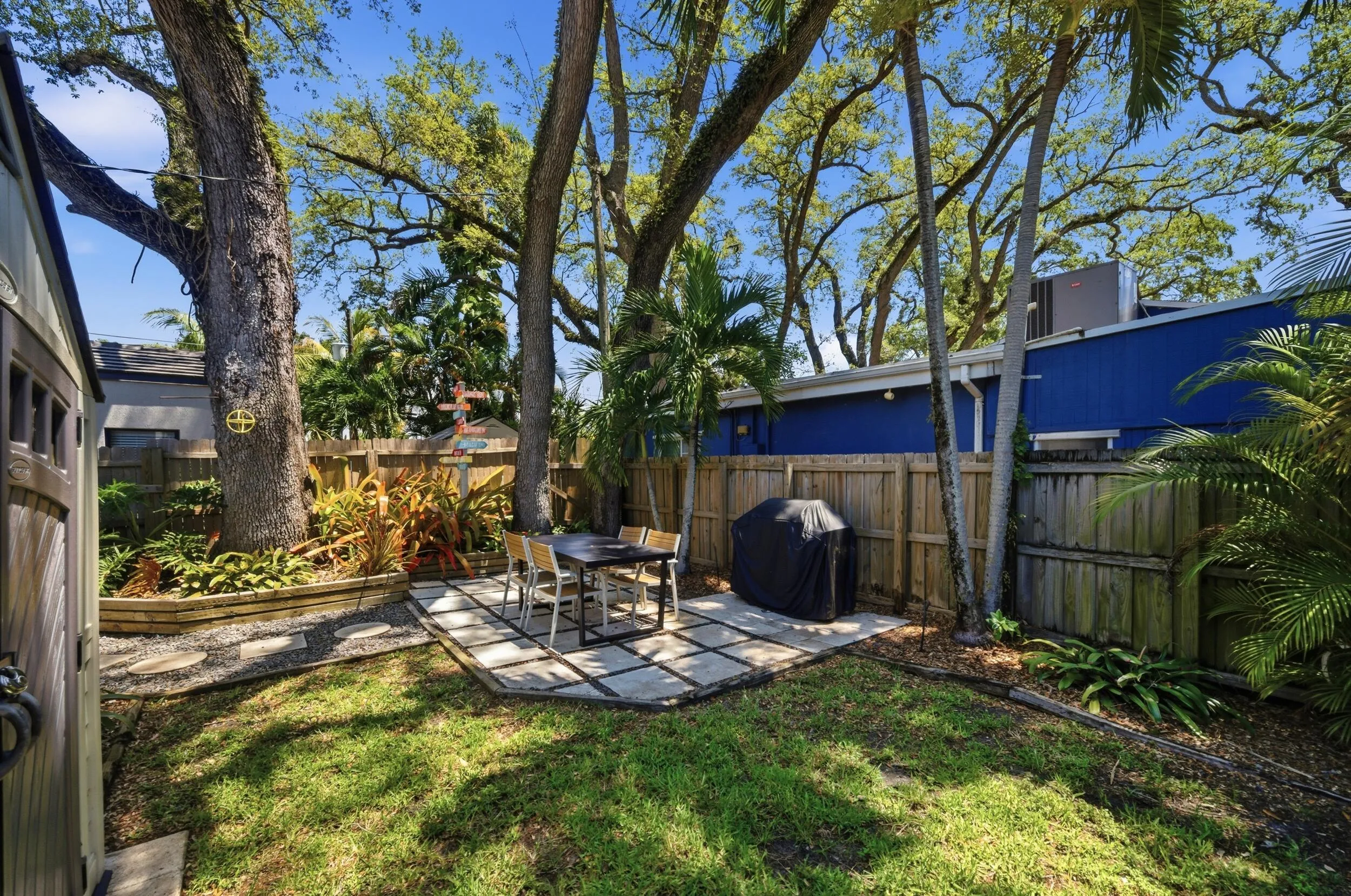 Expansive backyard featuring a central patio with large paver stones, surrounded by a manicured lawn