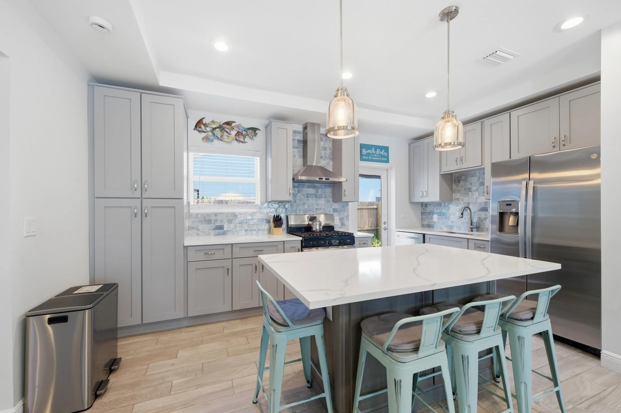 Modern kitchen featuring a large center island with a white countertop and seating for four
