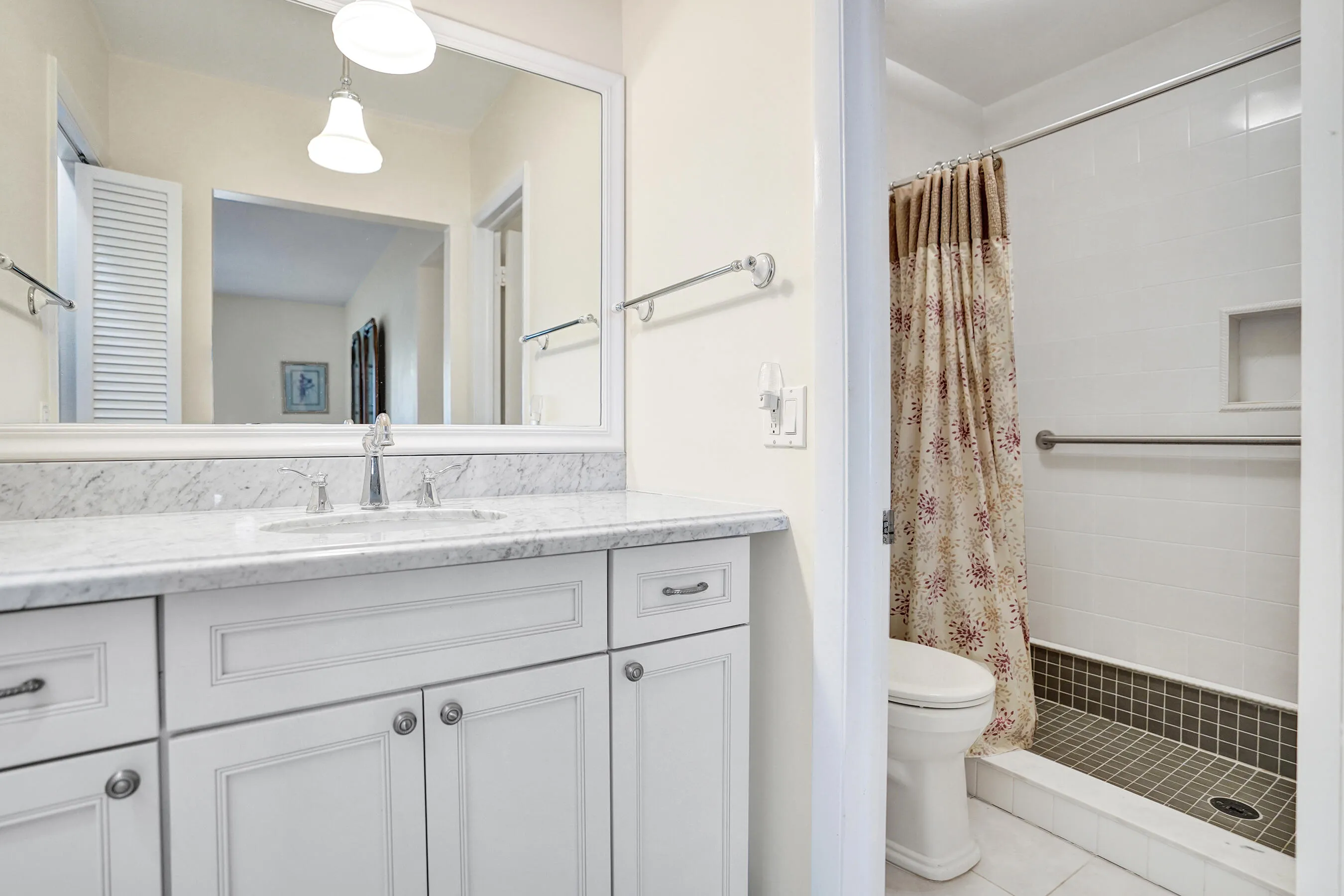 Primary Bathroom featuring a white vanity with a stone countertop, an undermount sink, and a large mirror