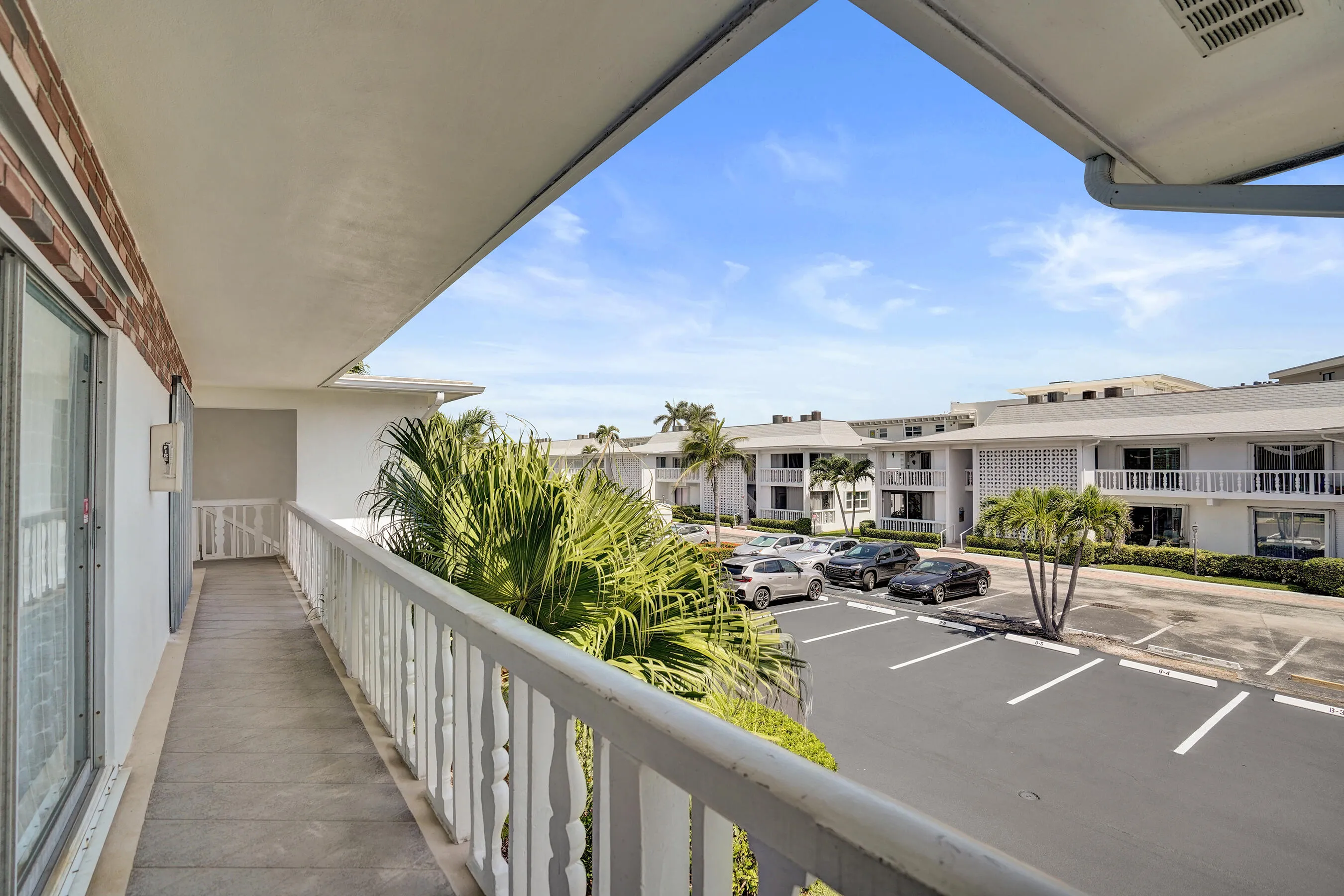 Expansive covered balcony featuring a concrete floor and white spindle railing
