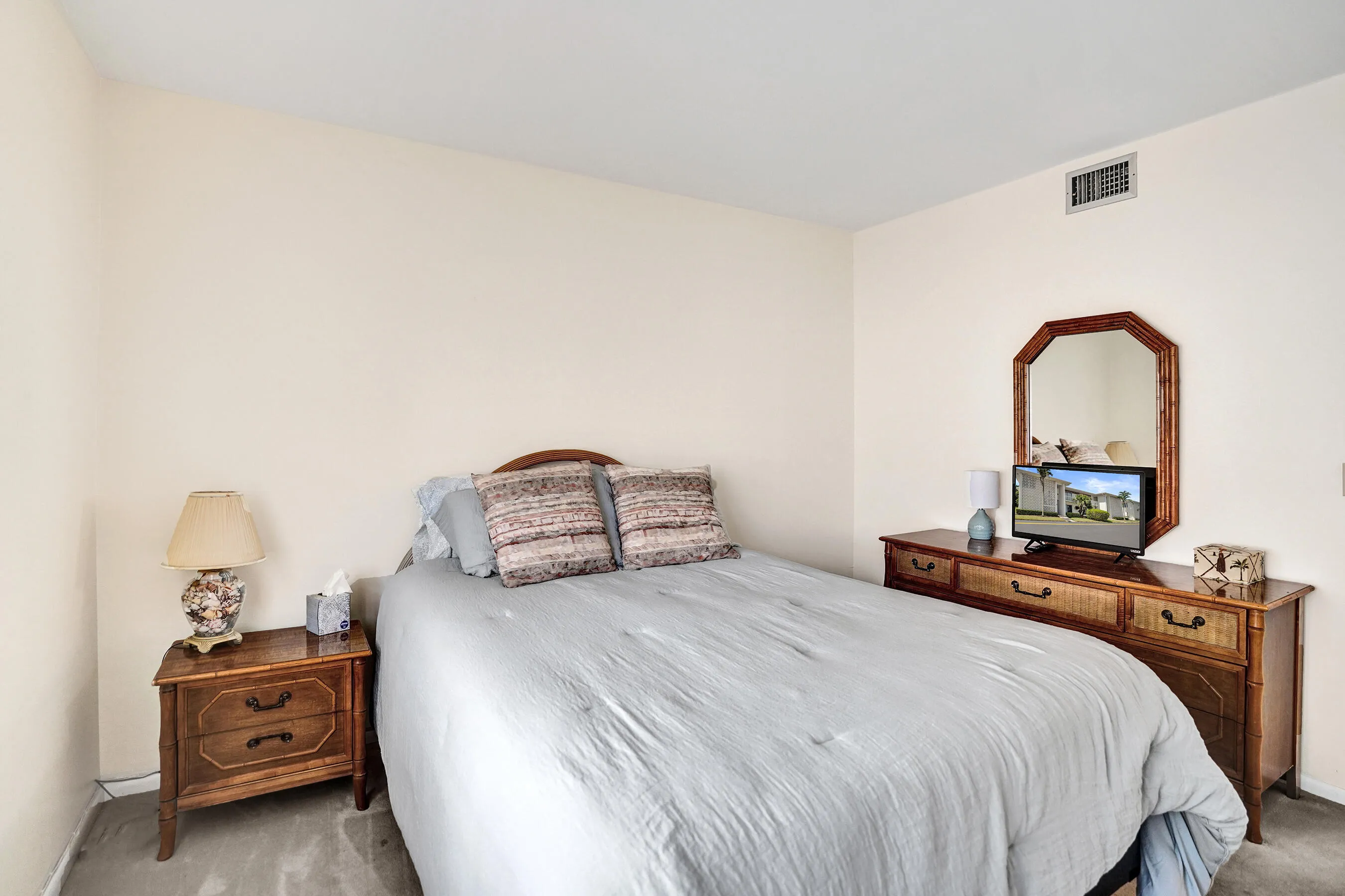 Bedroom featuring light-toned walls, a dark wood-finish headboard, and a corresponding nightstand