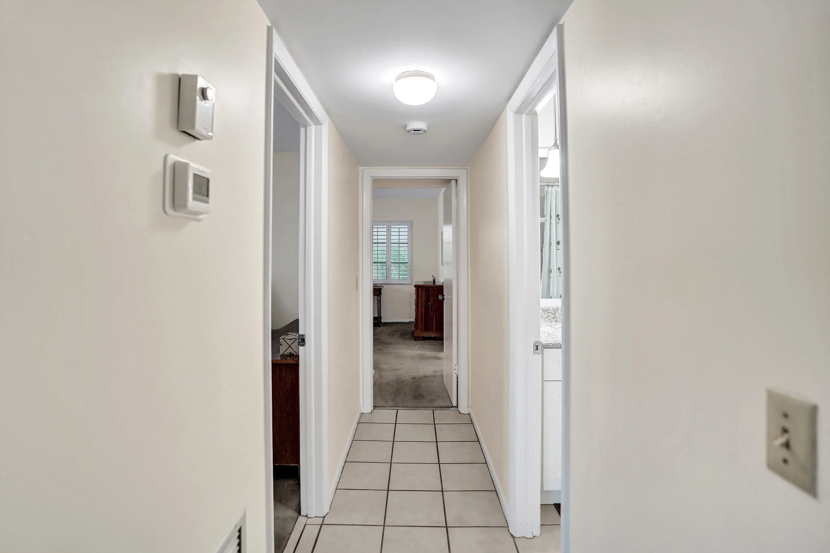 Neutral painted hallway with square tile flooring