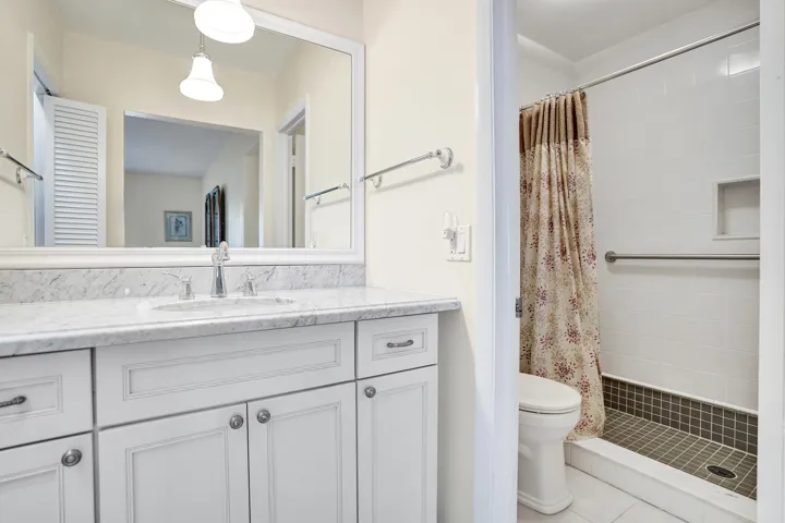 Primary Bathroom featuring a white vanity with a stone countertop, an undermount sink, and a large mirror