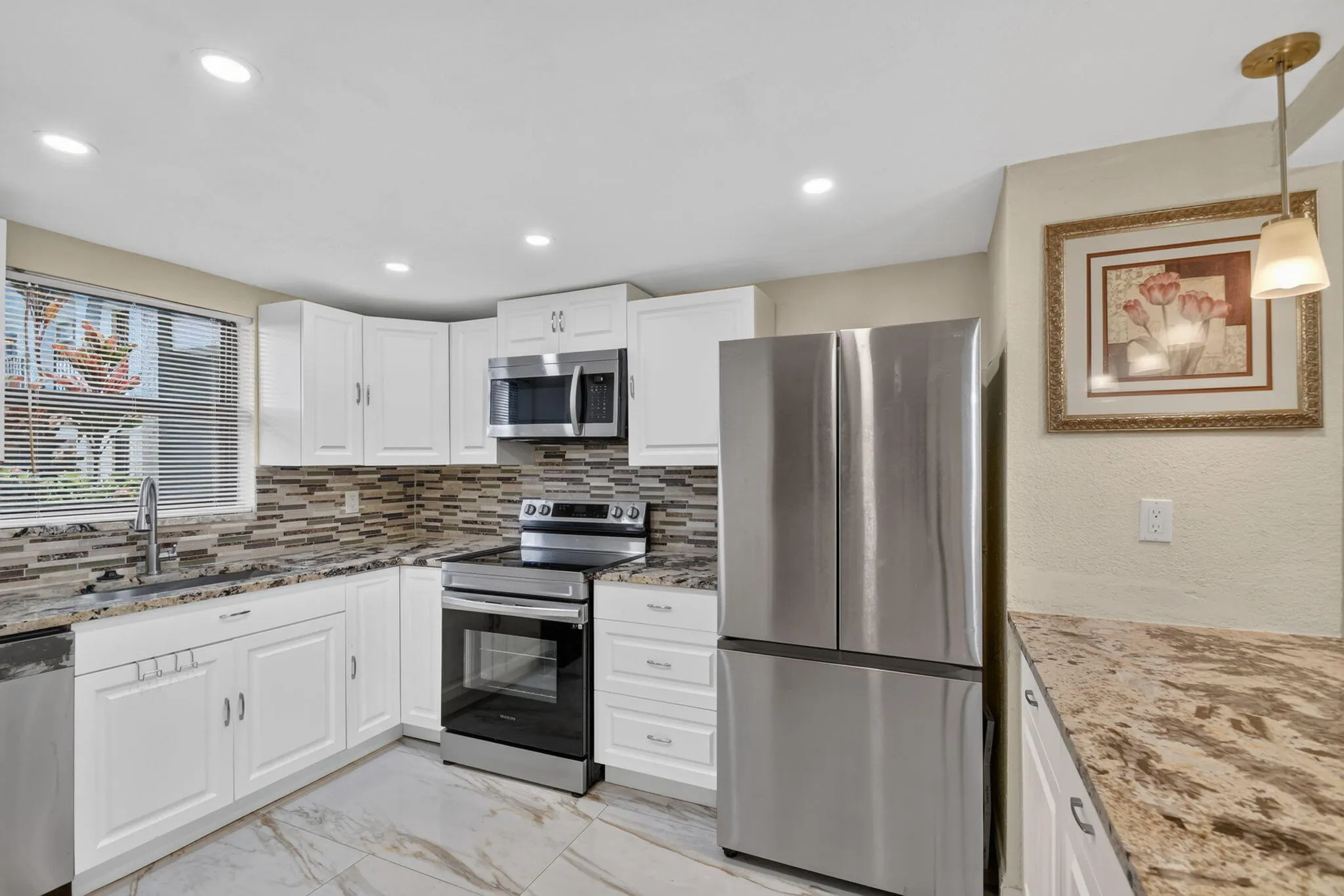 Kitchen featuring white cabinetry, stainless steel appliances, patterned tile backsplash, speckled countertops, and recessed lighting