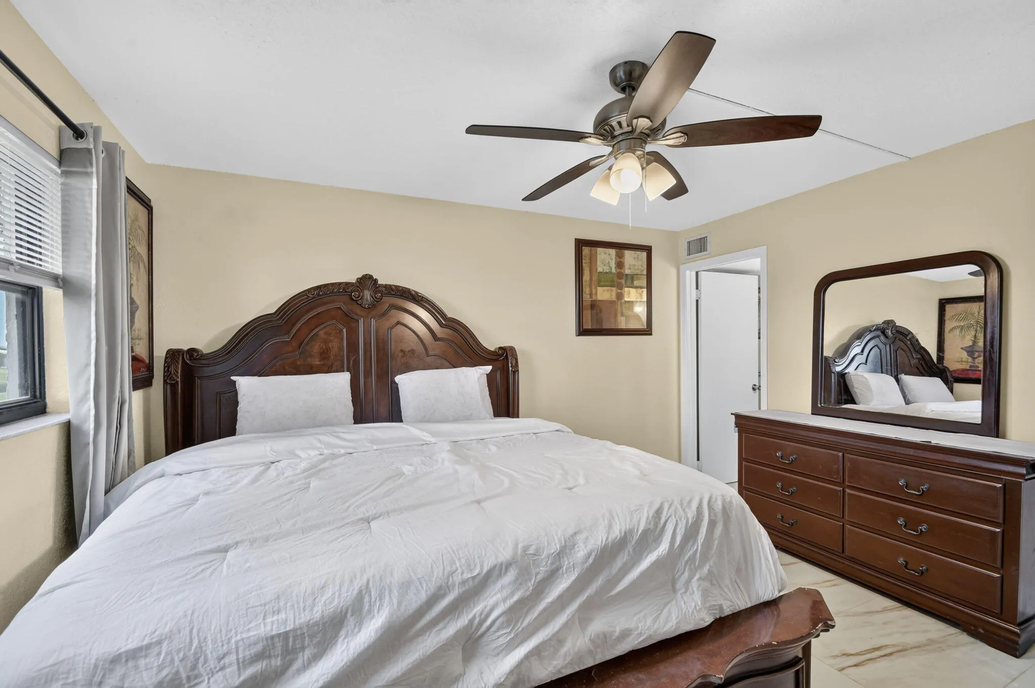 Spacious bedroom featuring light-colored walls and marble-look flooring