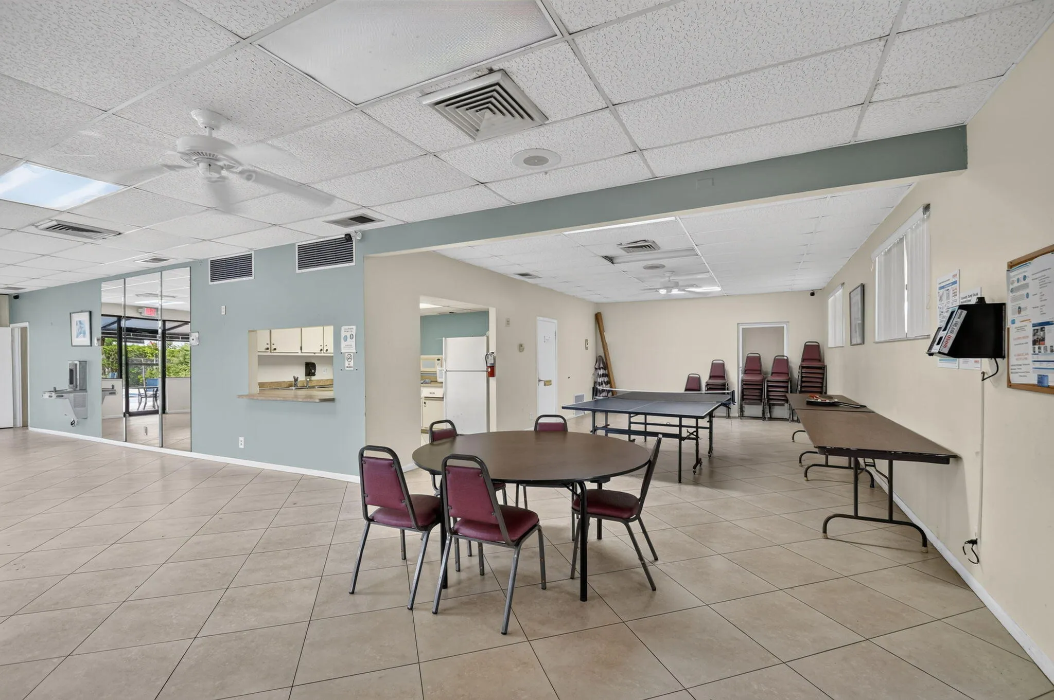 Spacious multi-purpose room featuring tiled flooring, a suspended acoustic ceiling, and recessed lighting