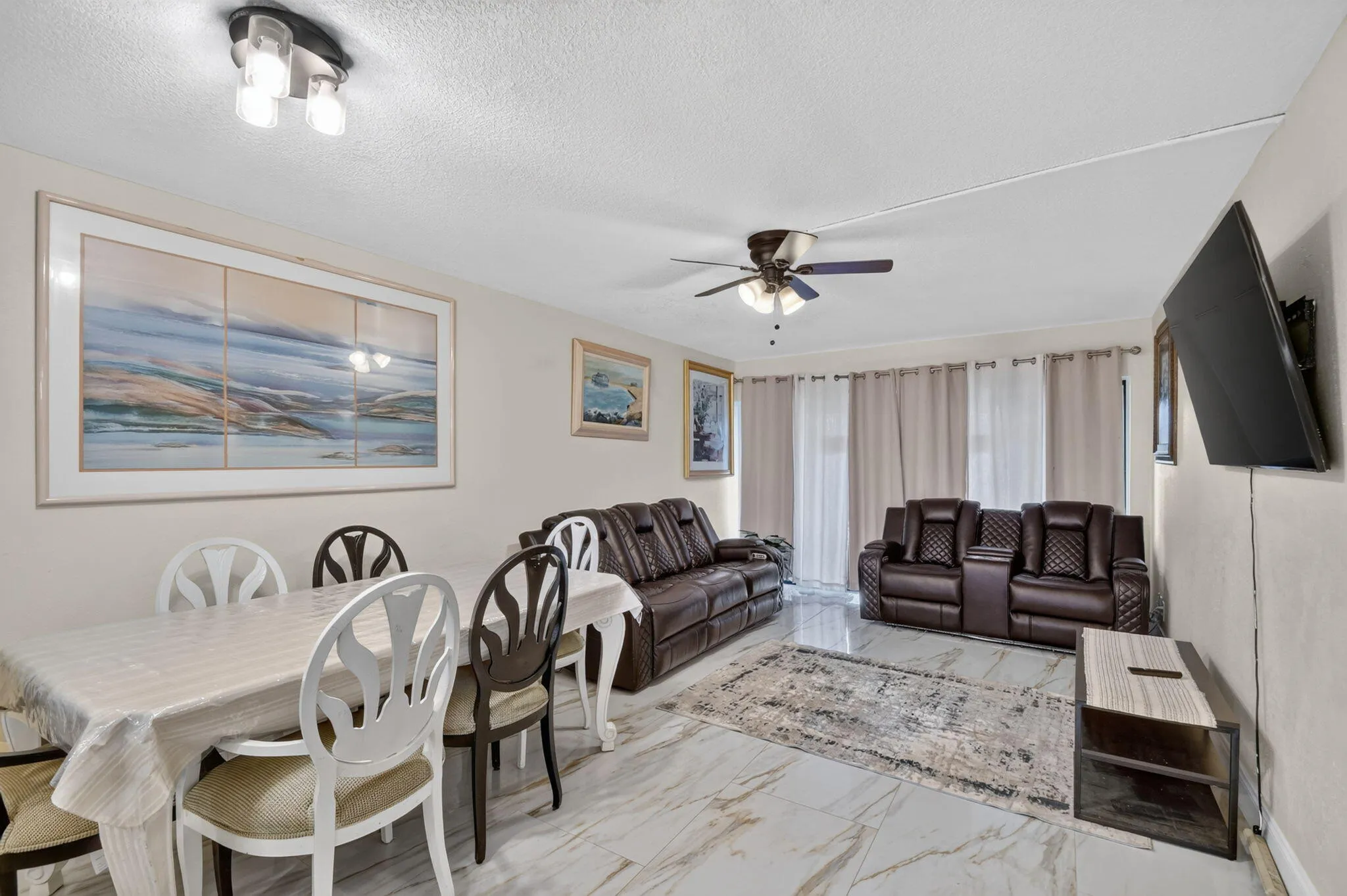 Open-concept living space with large format tile flooring and neutral wall tones
