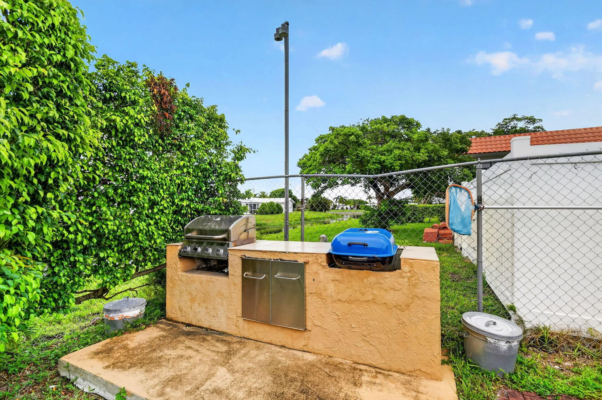 Outdoor built-in grill station featuring a stucco base with integrated stainless steel doors and a concrete countertop