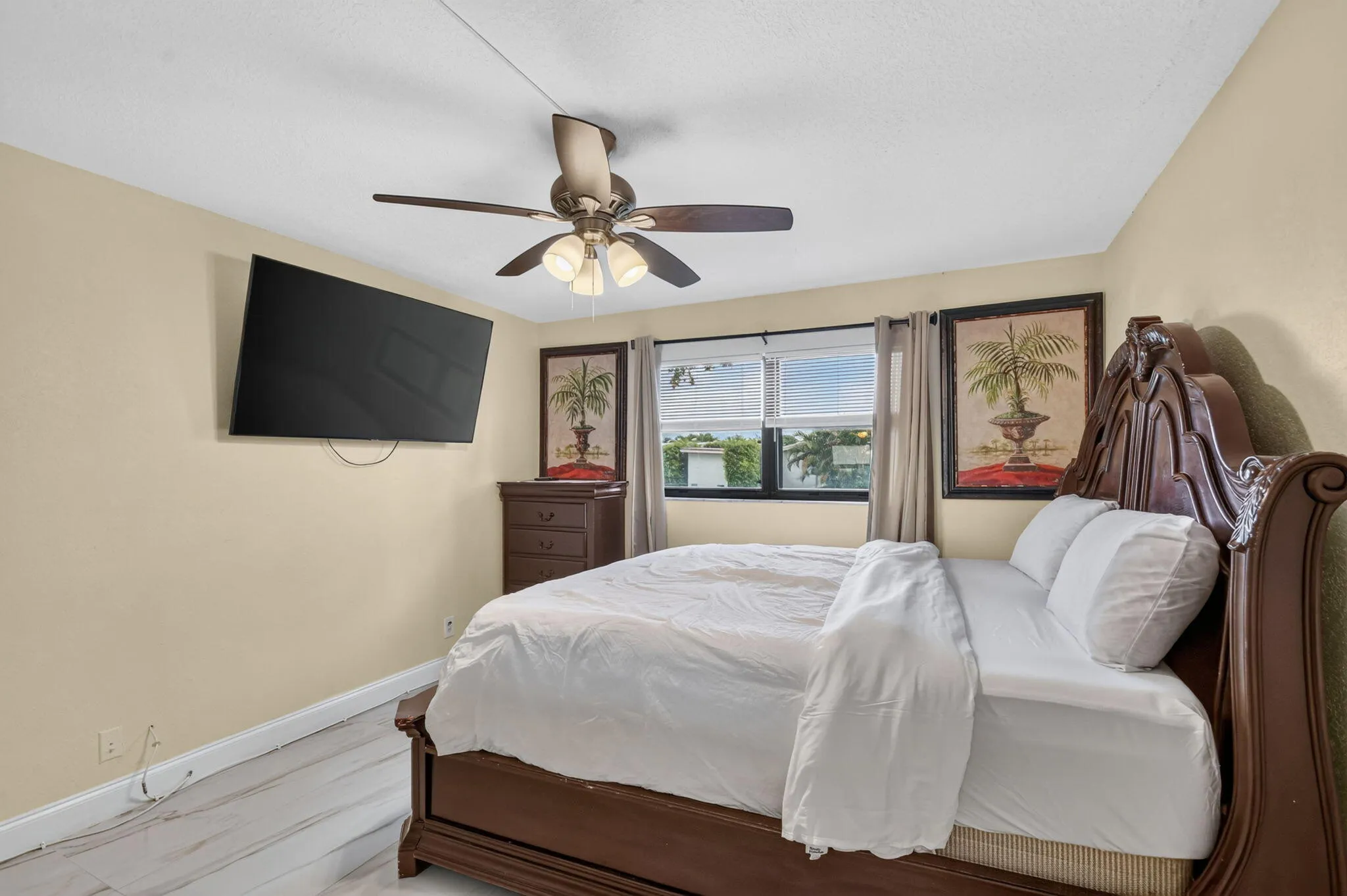 Bedroom featuring light wood-finish flooring, a ceiling fan with integrated lighting, and a window with vertical blinds and drapes