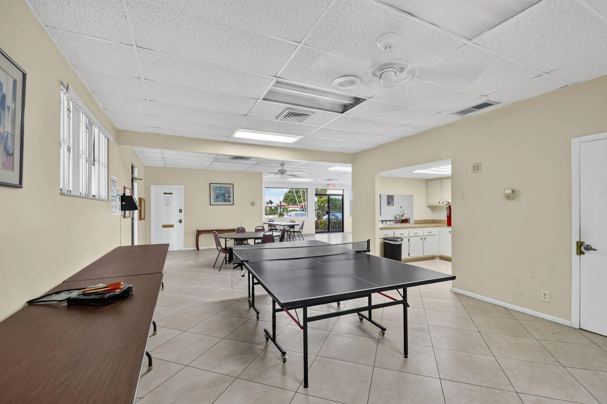 Spacious common room featuring a game table, neutral wall tones, and tiled flooring