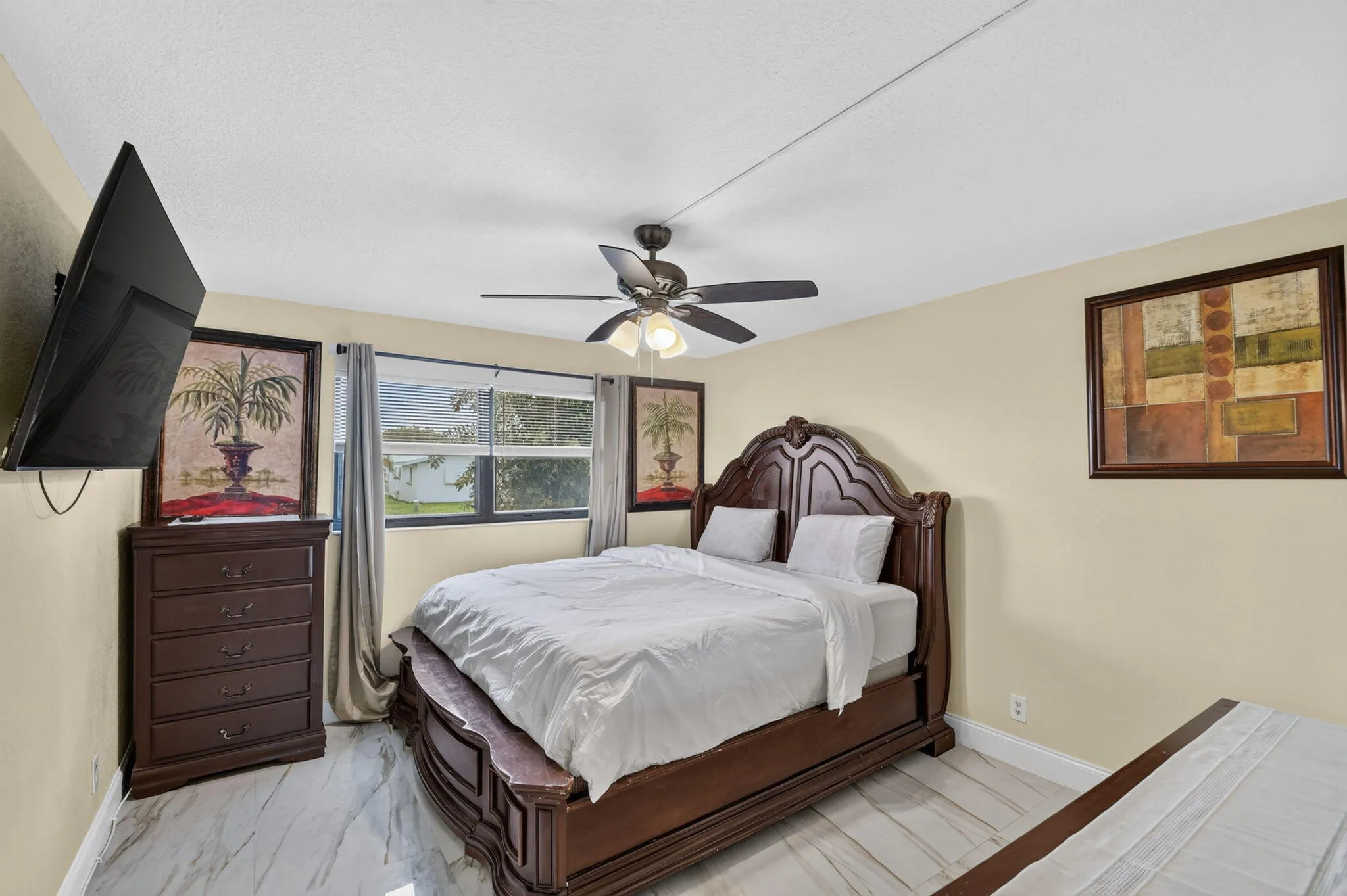 Bedroom featuring light-toned walls, a ceiling fan with integrated lighting, and light-colored flooring