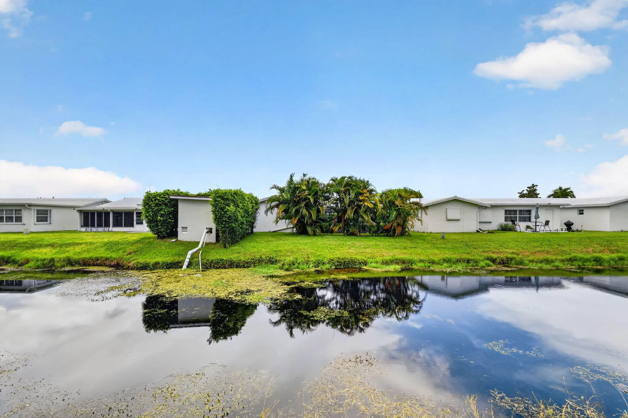 Waterfront property featuring a grassy lawn and mature landscaping