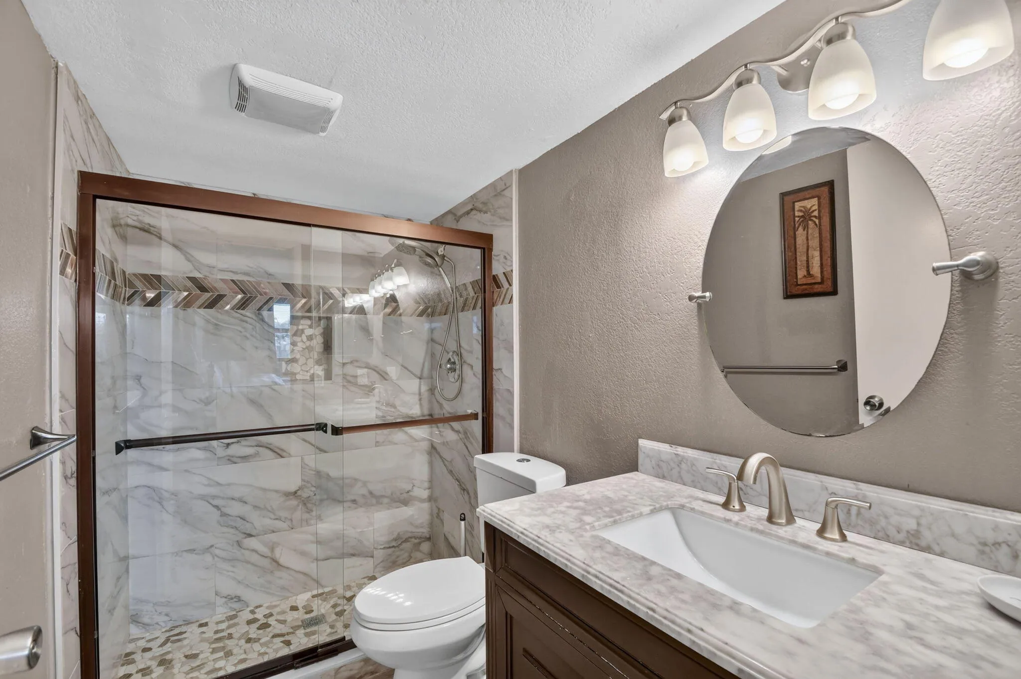Bathroom featuring a glass-enclosed shower with tile surround and pebble flooring