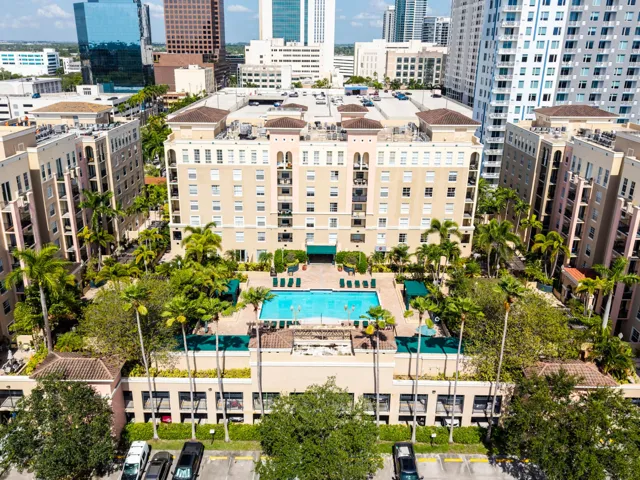 Resort-style pool deck featuring a heated pool, spa, outdoor TVs, bar, showers, and lush tropical landscaping.