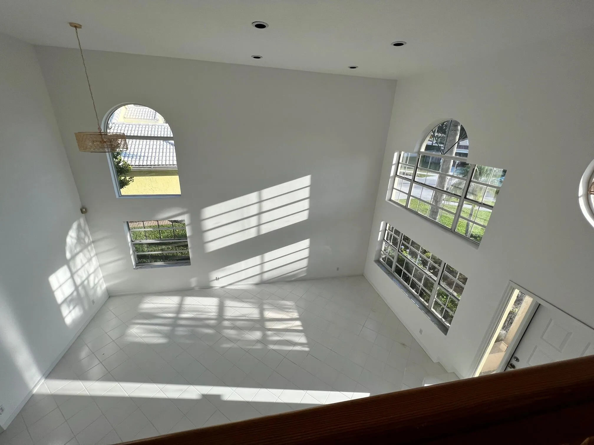 Soaring ceilings define this expansive room, featuring multiple arched and rectangular windows