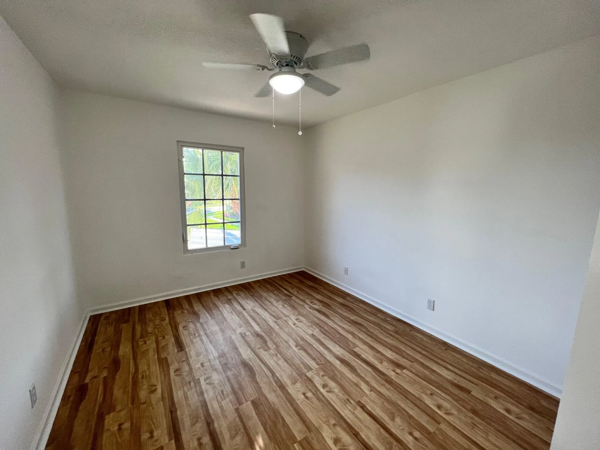 Bright interior room featuring wood-finish flooring, white baseboards, and a neutral wall palette