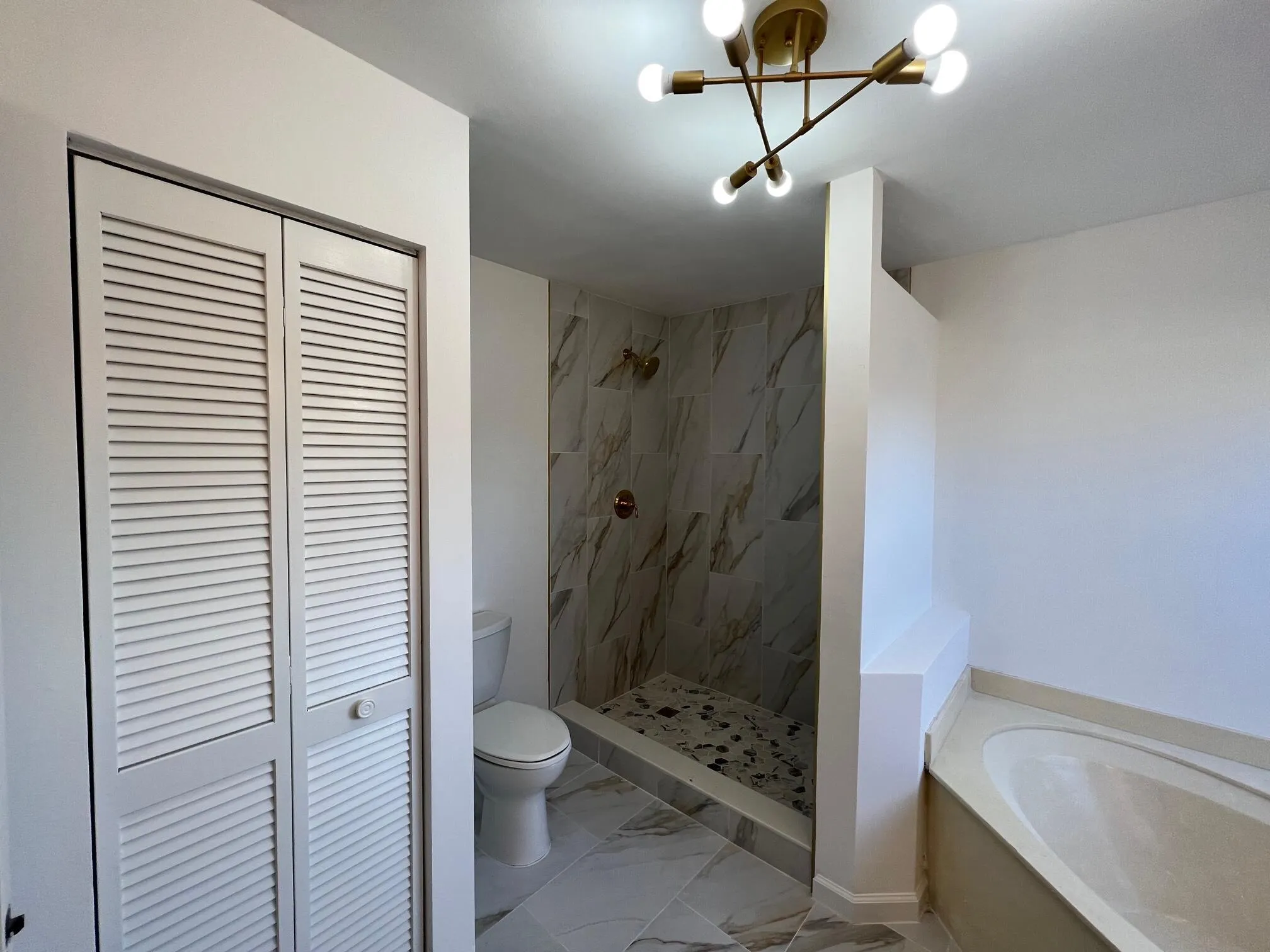 Walk-in shower with marble-look tile surround and contrasting pebble-tile floor