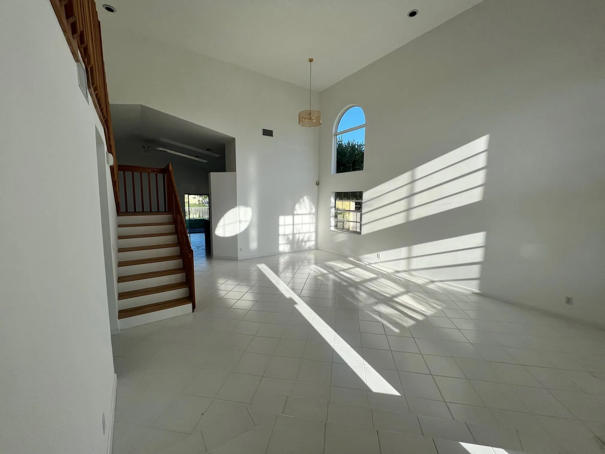 Vaulted ceiling great room with white tile flooring and white walls