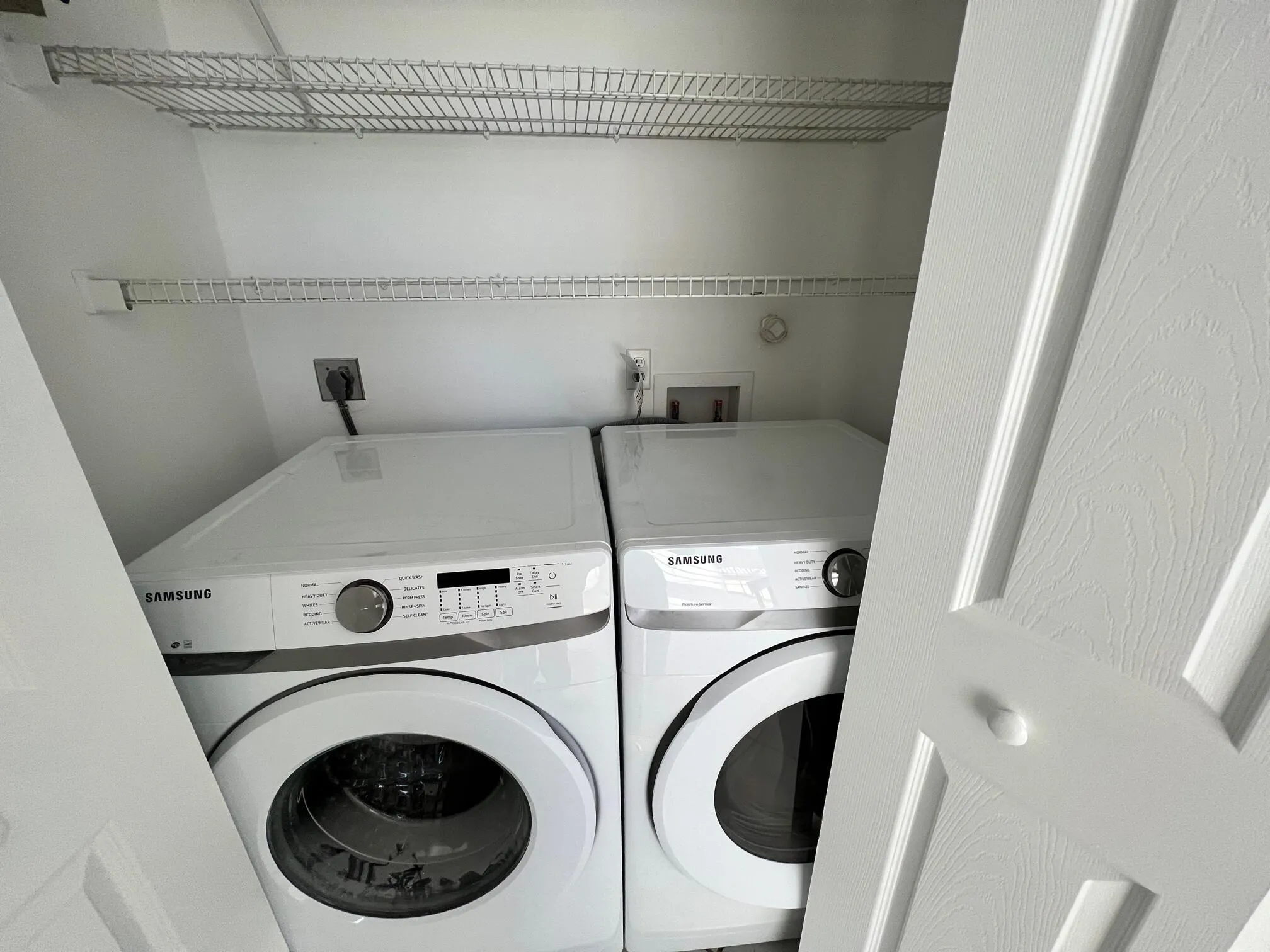 Dedicated laundry area with white paneled bifold doors, integrated shelving, and appliance hookups
