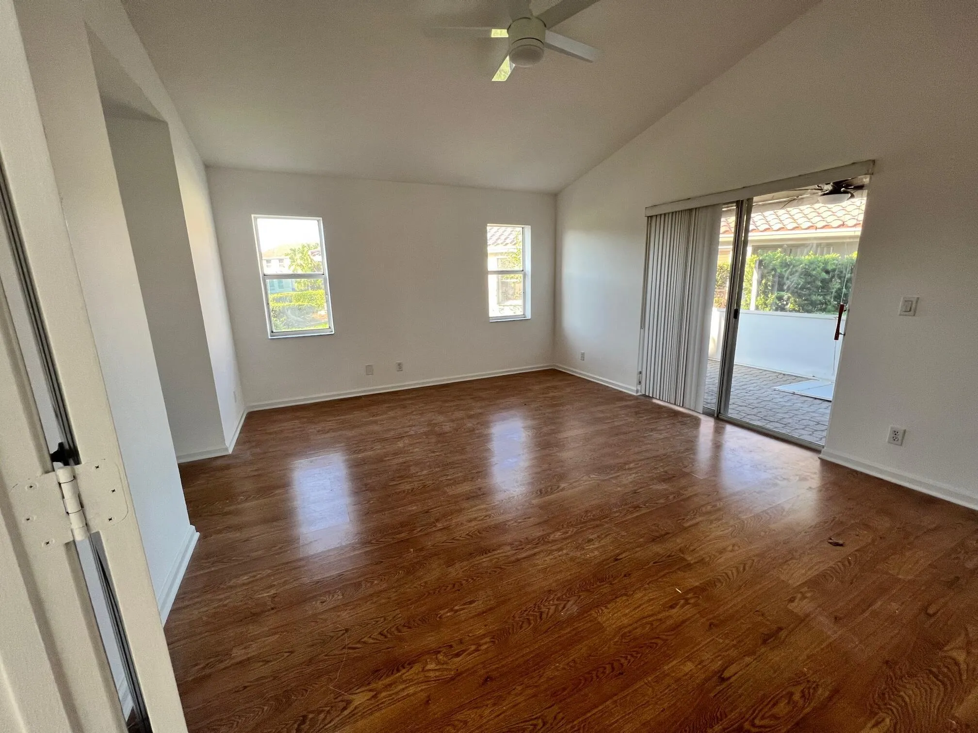 Spacious interior room featuring wood-finish flooring, vaulted ceilings, and a ceiling fan