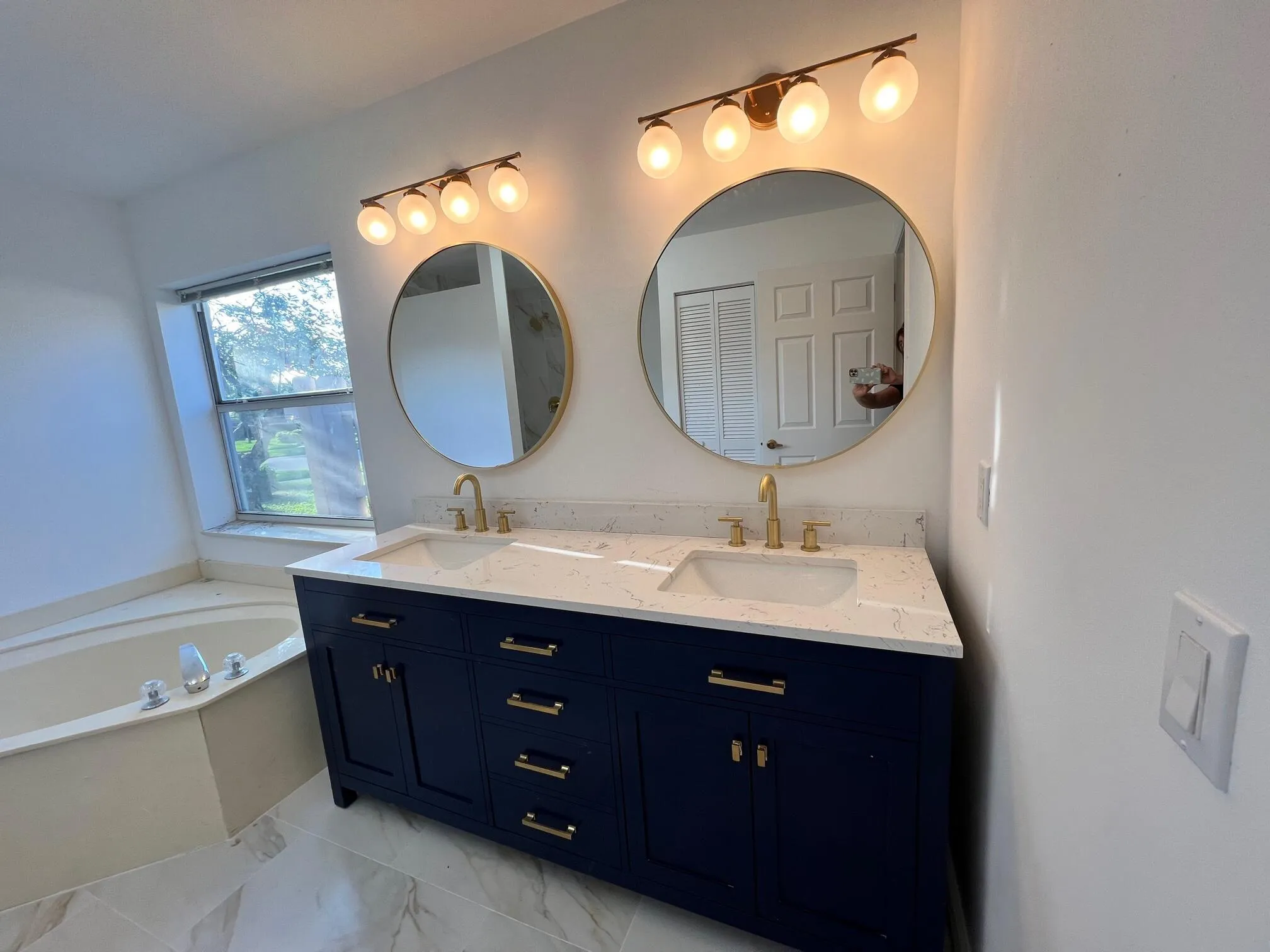 Dual navy blue vanities with gold hardware, white countertops, and integrated sinks