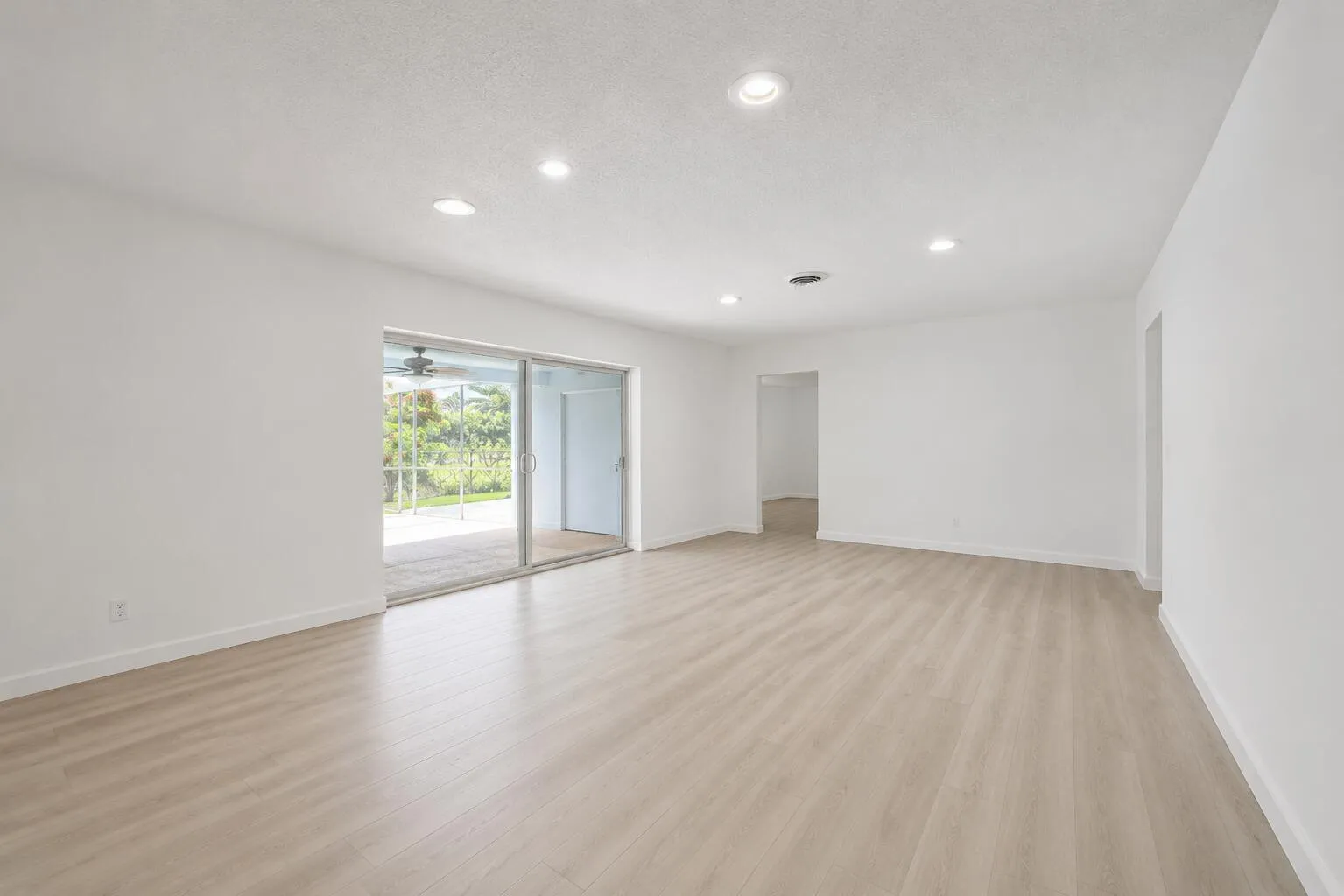 Spacious room featuring wood-finish flooring, recessed lighting, and white baseboards