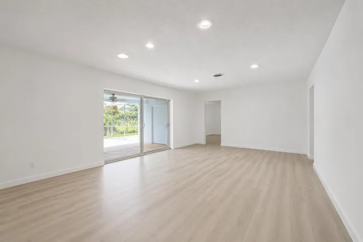Spacious room featuring wood-finish flooring, recessed lighting, and white baseboards