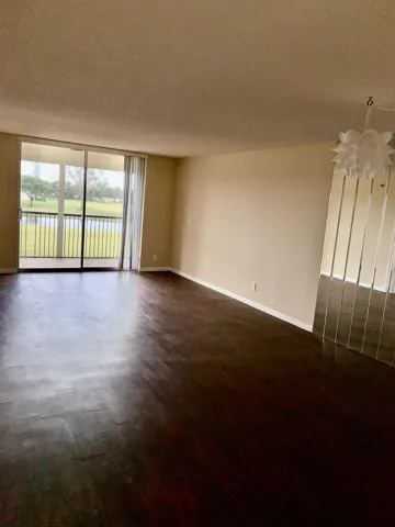 Spacious interior featuring dark wood-finish flooring, neutral wall tones, and a sliding glass door leading to a private balcony