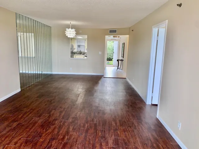 Spacious interior featuring wood-finish flooring, neutral-toned walls, and a decorative mirror wall accent