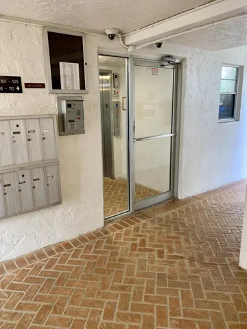Entryway featuring a herringbone brick floor pattern, white stucco walls, and a glass-paneled entry door