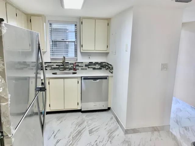 Kitchen featuring white cabinetry, a stainless steel refrigerator, and a coordinating stainless steel dishwasher