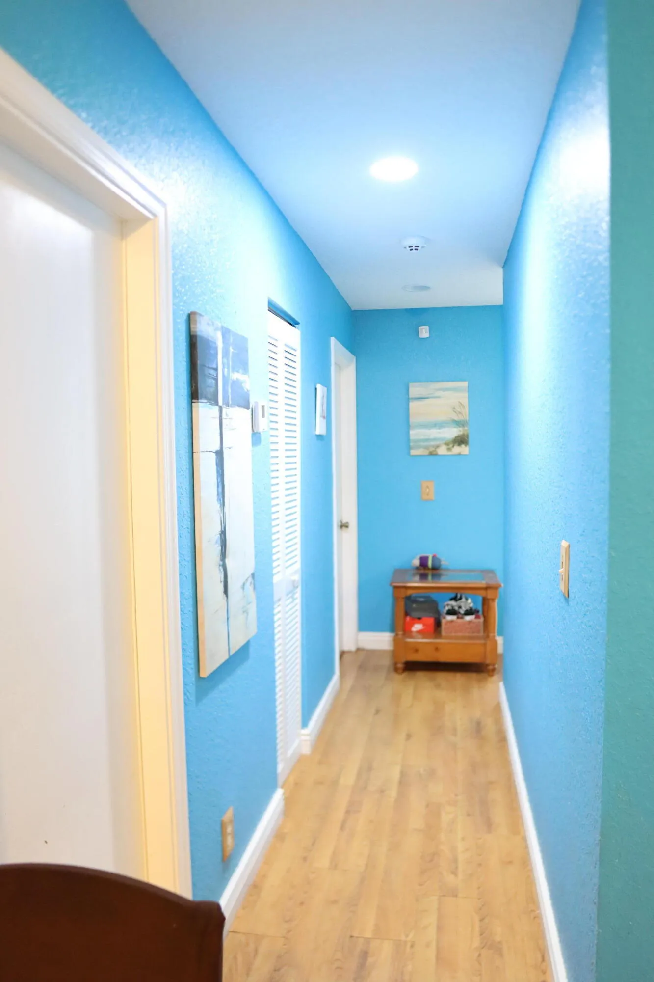 Hallway with laminate flooring, recessed lighting, and a white louvered door