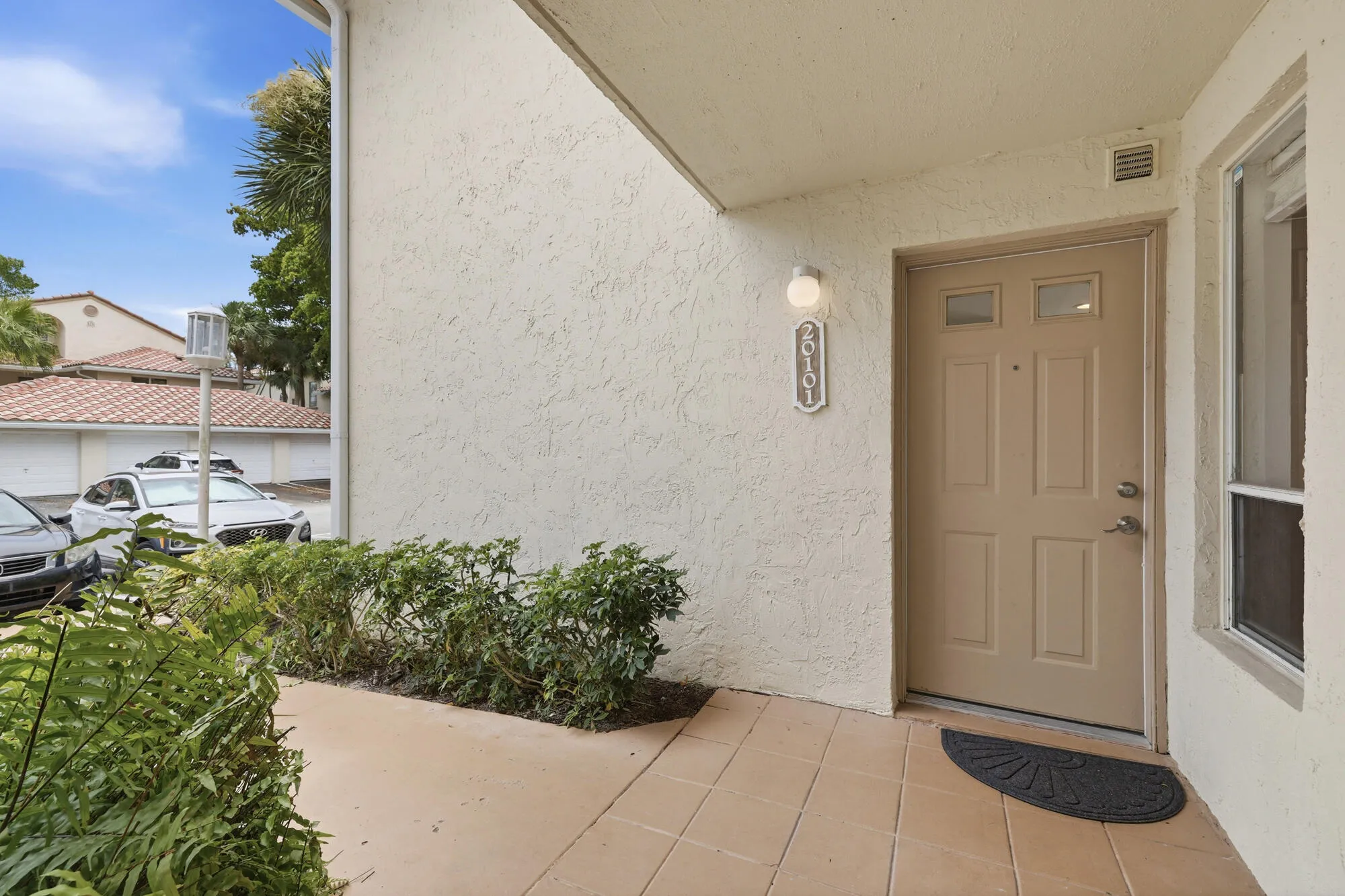 Entryway featuring a paneled door with glass inserts, textured stucco exterior, and a contemporary wall-mounted light fixture