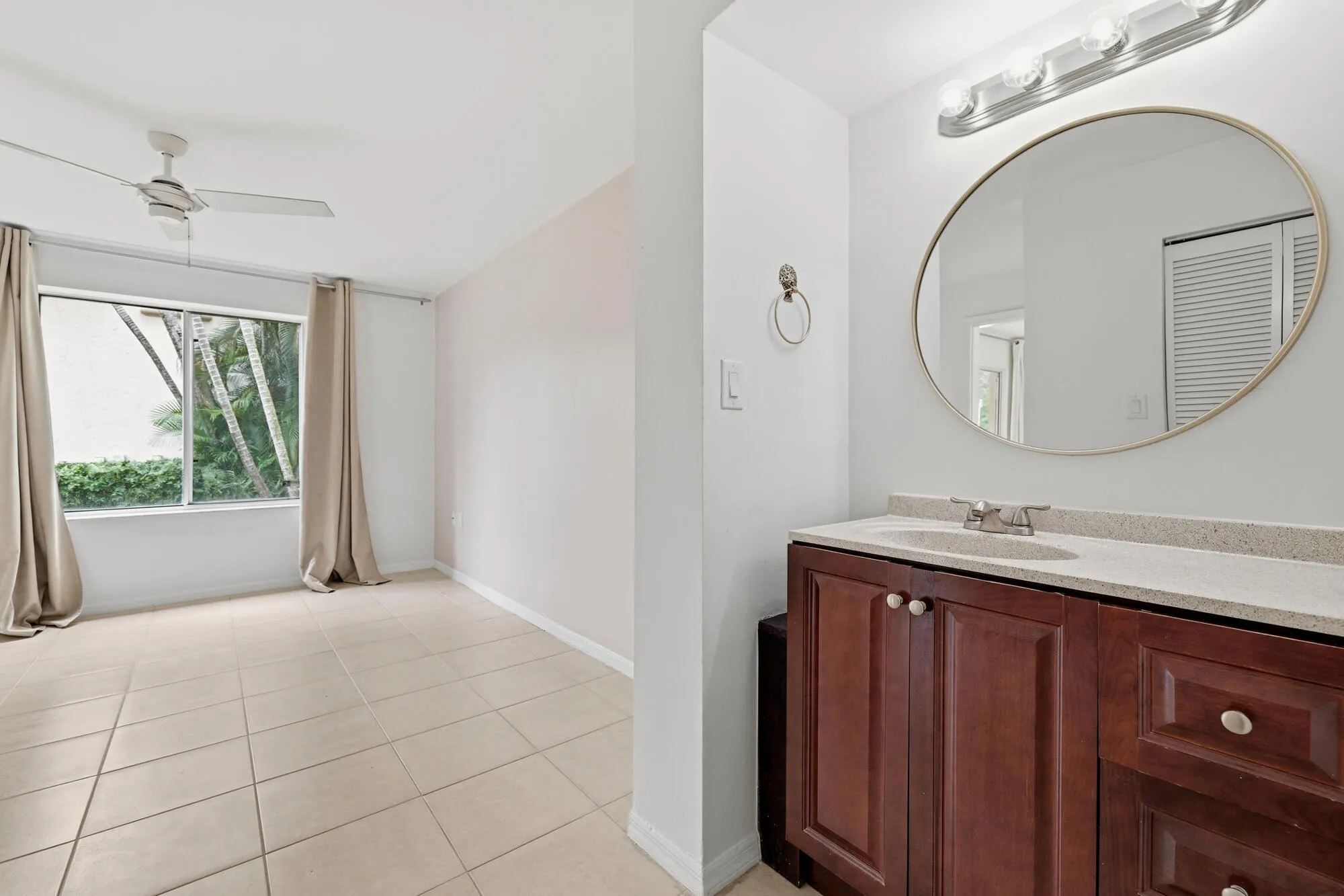 Bathroom vanity featuring a light-toned countertop, undermount sink, and dark wood-finish cabinetry