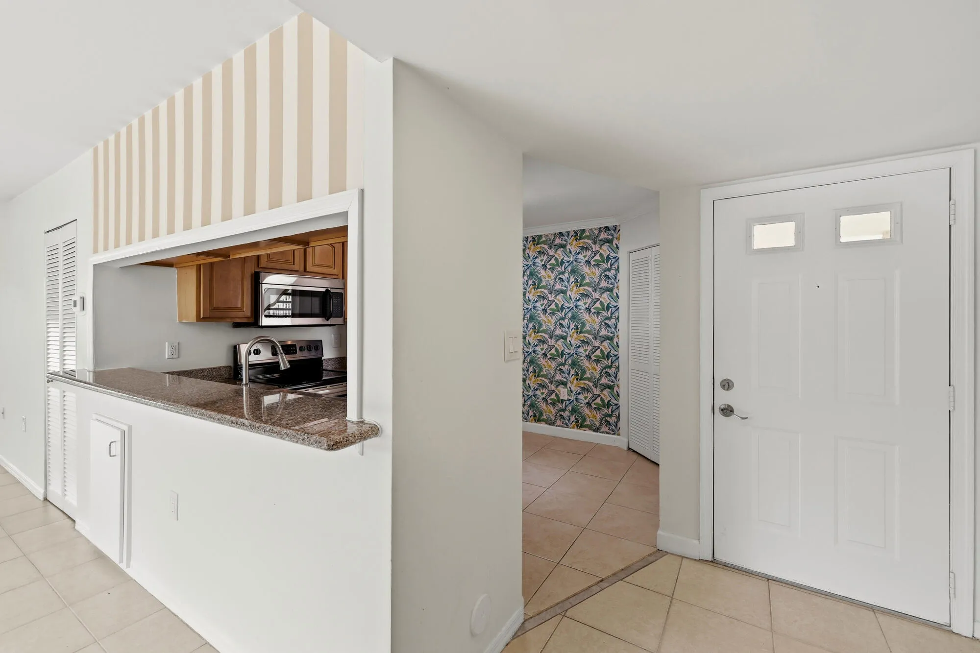 Kitchen pass-through with a granite countertop, wood cabinetry, and stainless steel appliances