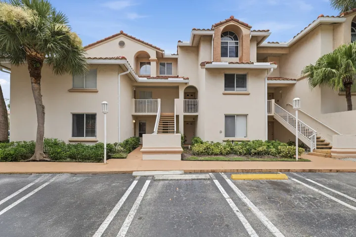 Ground-floor condominium with Mediterranean-inspired architecture, a stucco exterior, and terracotta-style roof tiles.