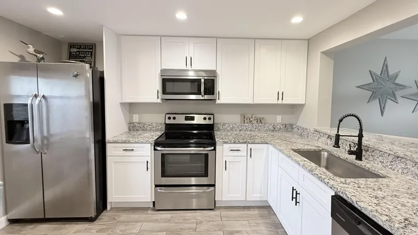 White cabinets, granite counters, SS appliances, & a nook for eat-in seating.