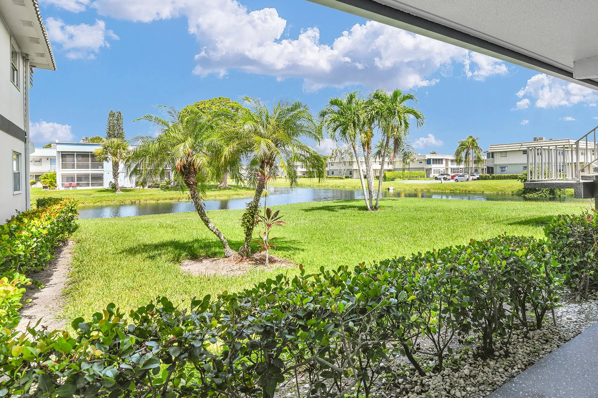 Expansive canal-front property featuring lush green lawns, mature palm trees, and clear blue water
