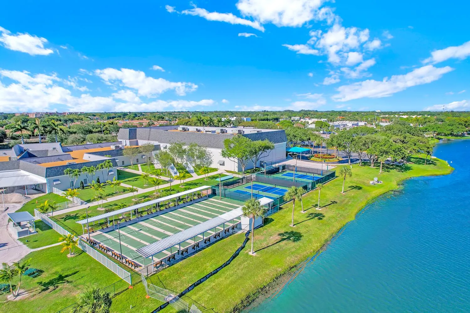 Expansive property featuring multiple outdoor amenities, including several tennis courts and covered recreational areas