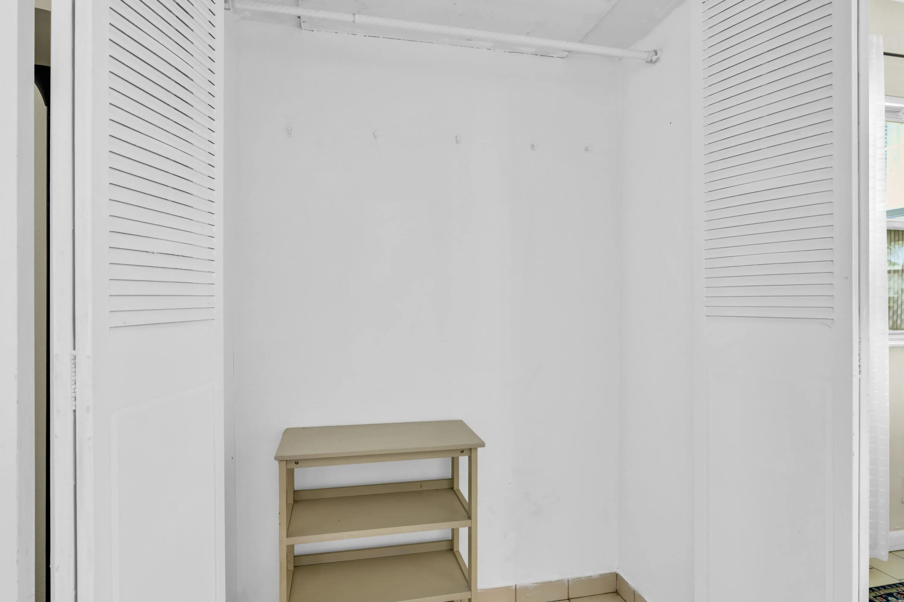 Recessed storage area with louvered bi-fold doors, white interior walls, and tile flooring