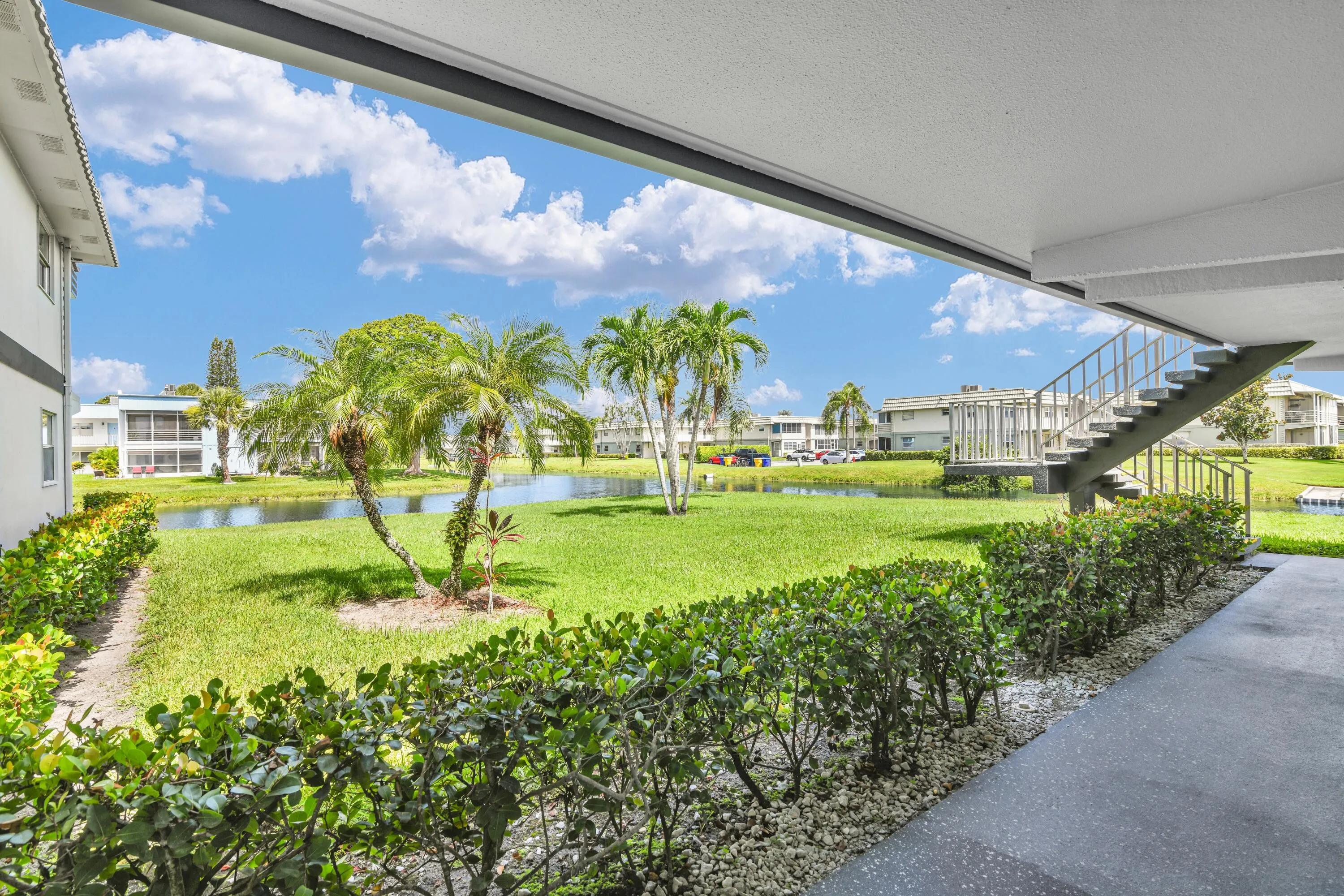 Lush green landscaping frames a tranquil water feature with mature palm trees