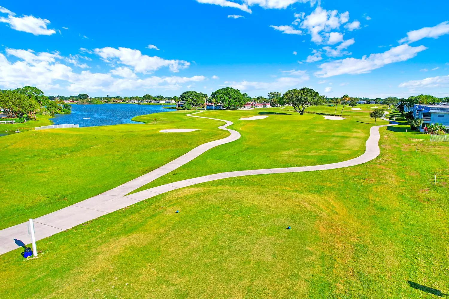 Expansive golf course setting featuring manicured greens and winding cart paths