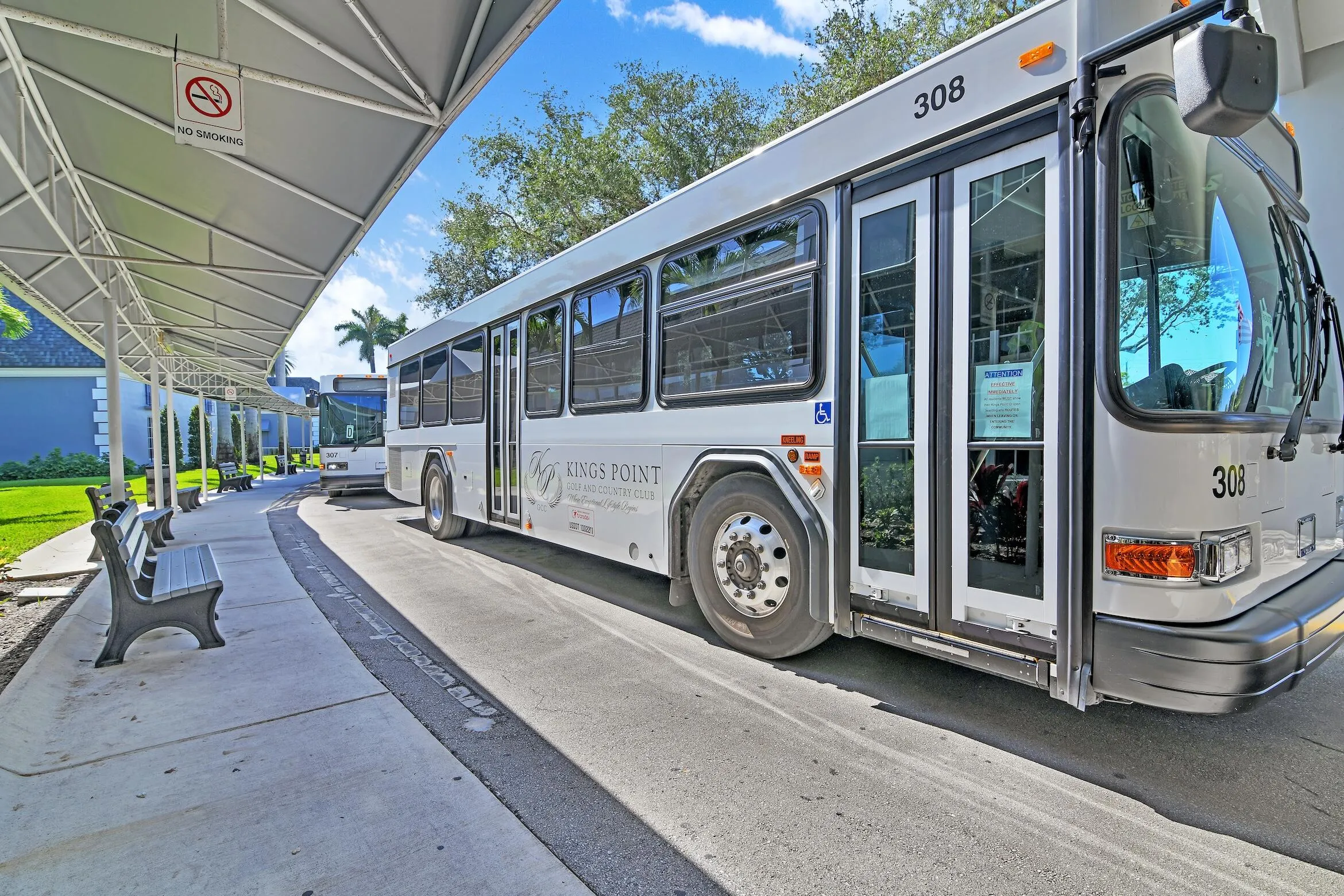 Covered walkway with multiple benches and a visible bus service